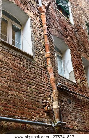 Medieval Clay Downspout On Street Vicolo Degli Orefici In Old City Siena, Tuscany, Italy