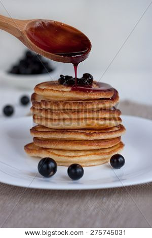 Stack Of American Pancakes With Blackcurrant Jam Is Dripping From A Spoon.