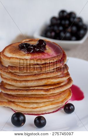 Stack Of American Pancakes With Blackcurrant Jam And Fresh Blackcurrant Berries Are Lying On A White