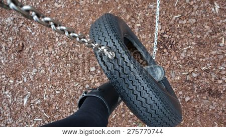 Playing In A Playground, Foot Swinging Across A Tyre Chain Bridge With Wood Chips Below