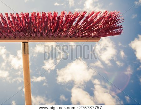 Broom Red Sweeping Brush Against Blue And White Cloudy Sky. Household Obejcts Concept.