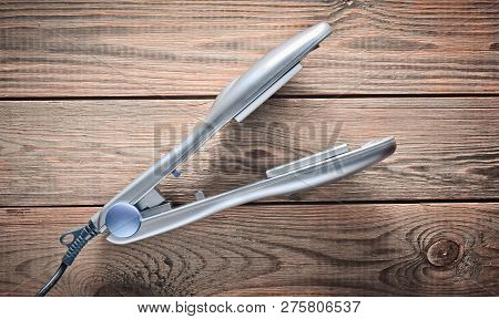 Iron For Leveling Hair On A Wooden Table. Hair Straighteners. Top View.
