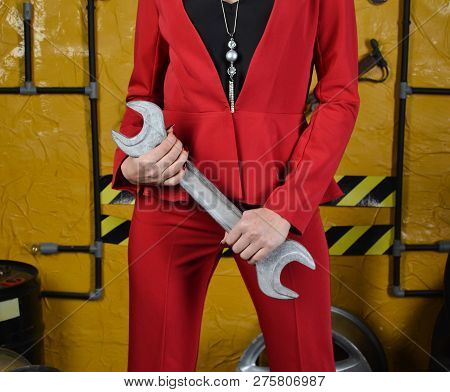 Fashionable Mechanic Girl In Trendy Clothes Is Holding A Wrench On The Background Of The Workshop Of