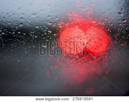 Abstract Pattern Of Colorful Lights And Rain Drops During Downpour On Winshield Of Car After Dark