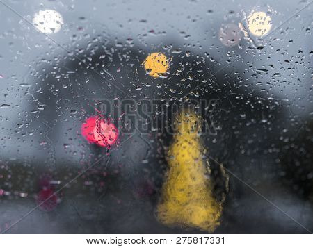 Abstract Pattern Of Colorful Lights And Rain Drops During Downpour On Winshield Of Car After Dark
