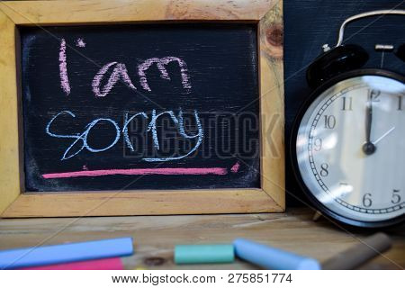 I Am Sorry. Back To School Concept. Alarm Clock On Wooden With Blackboard On Background
