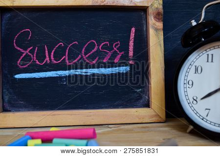 Success. Back To School Concept. Alarm Clock On Wooden With Blackboard On Background