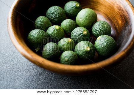 Immature Unripe Organic Green Limes In Wooden Bowl.