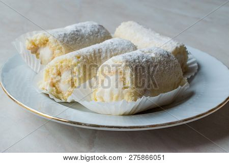 Mini Roll Cake With Vanilla Cream, Coconut And Powdered Sugar.