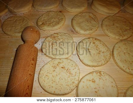 Italian Tigelle Ready To Be Cooked On A Knotted Table Near A Rolling Pin