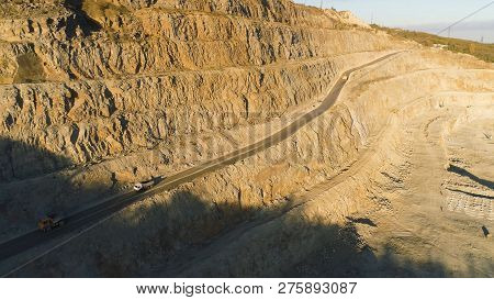 Top View Of Quarry With Trucks. Shot. Multistage Pit Wall For Mining And Passing On Her Road For Tru