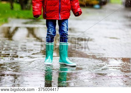 Close-up Of Kid Wearing Yellow Rain Boots And Walking During Sleet, Rain And Snow On Cold Day. Child