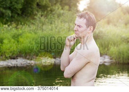 A Discontented Man With A Naked Torso Looks Thoughtfully At The Shore And Stands Waist Deep In The R