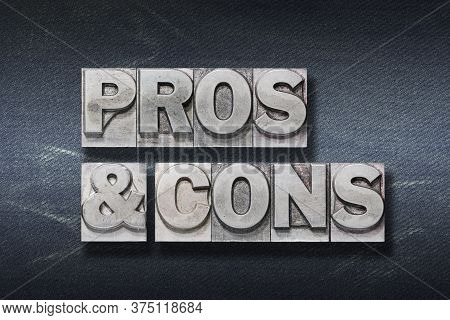 Pros & Cons Phrase Made From Metallic Letterpress On Dark Jeans Background