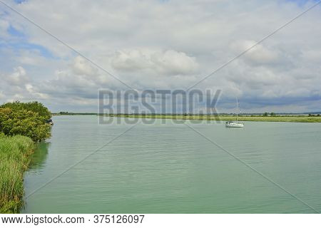 A Boat Sails Down The Waters Of The Wetlands Of Isola Della Cona In Friuli-venezia Giulia, North Eas