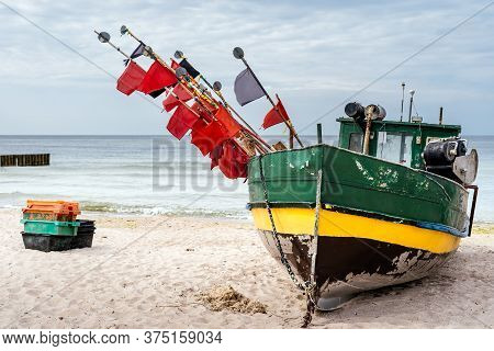 Old And Rusty Fishing Boat And Equipment On Sandy Beach, Getting Ready For Fishing Trip. Blue Sea In