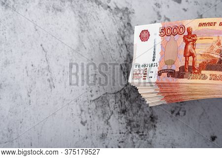 Russian Cash Banknotes Of Five Thousand Rubles, The Bundle Hangs On A Gray Background.