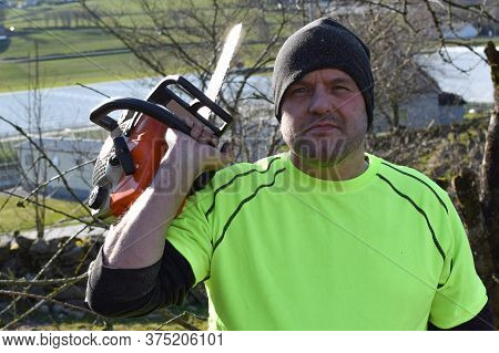 Worker In The Garden With A Chainsaw. Concept: Spring Garden Work. Close-up.