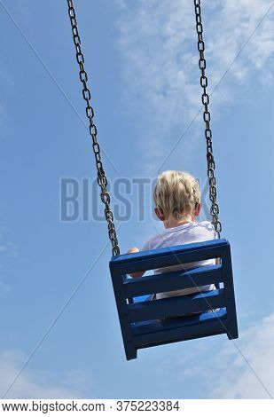 A Boy With Cochlear Implants Riding Swing In Summer Park