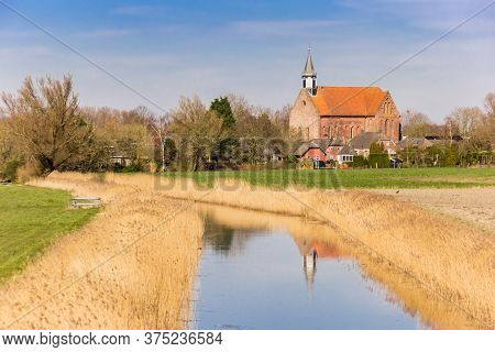 Historic Stefanus Church With Reflection In The River In Holwierde, Netherlands