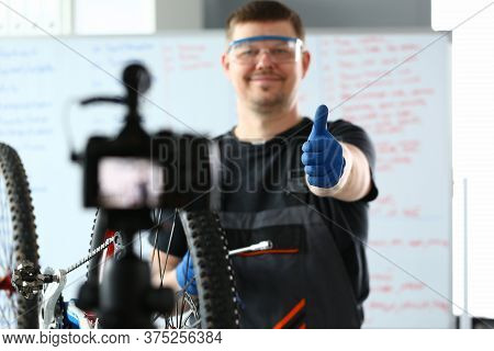 Happy Male Worker In Special Clothes Repairing A Bicycle And Shooting Video Content