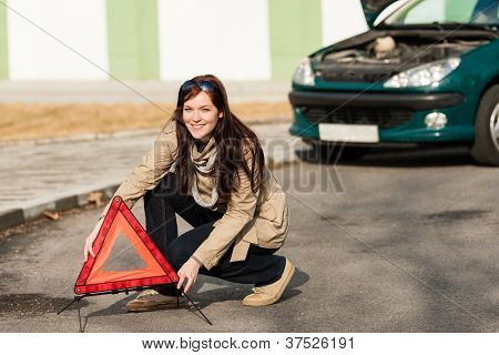 Donna mettendo il triangolo d'avvertimento sul cartello stradale auto ripartizione