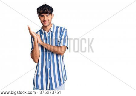 Young hispanic man wearing casual clothes clapping and applauding happy and joyful, smiling proud hands together 