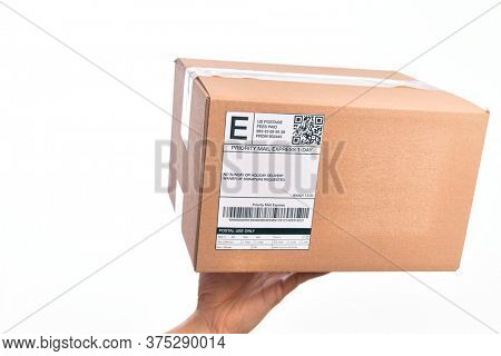 Hand of caucasian young man holding cardboard package showing label with codebar over isolated white background