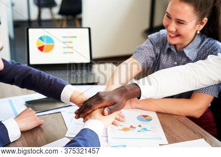 International Business Team Showing Unity With Their Hands Stacked Together In Pile. Black African-a
