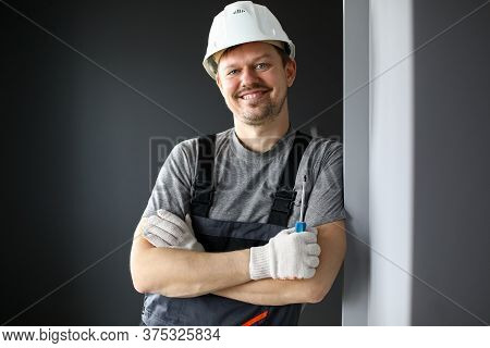 Male Builder In Coveralls And Hard Hat Smiling. Professional Cordless Screwdriver For Electricians. 