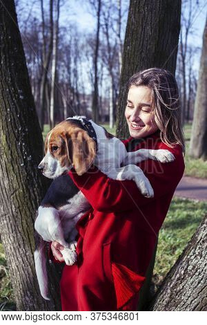 Pretty Young Girl In Redd Coat Playing With Dog Outside In Green Park, Lifestyle People Concept