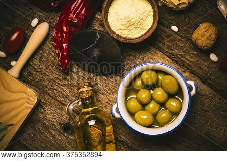 Extra Virgin Olive Oil, Green Olives And Food Ingredients,  Mediterranean Diet On Old Wooden Table.