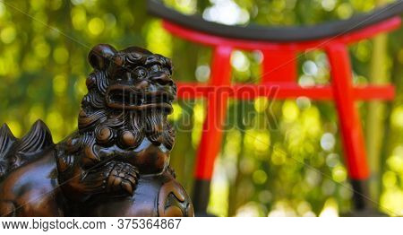 Red Torii Gate And Okinawan Statue In Bamboo Forrest