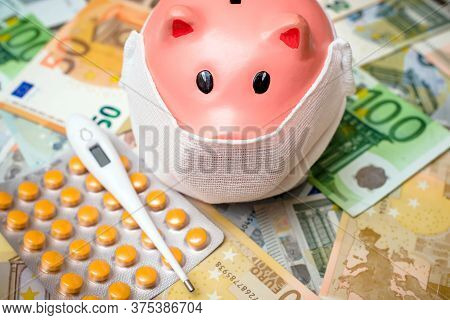 Piggy Bank In A Mask On A Background Of European Currency.the Concept Of Coronavrius Epidemic