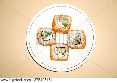 Sushi Rolls Lie In A White Plate On An Orange Background