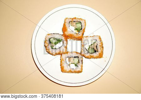 Sushi Rolls Lie In A White Plate On An Orange Background