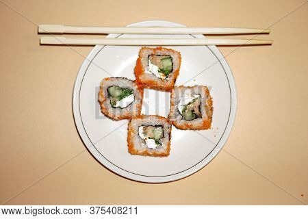 Sushi Rolls Lie In A White Plate On An Orange Background
