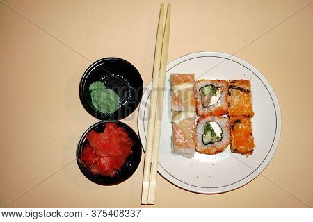 Sushi Rolls Lie In A White Plate On An Orange Background