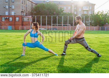 Attractive Young Couple Man And Woman 25 Years Old Are Doing Exercises On A Sunny Summer Morning On
