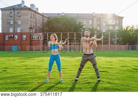 Attractive Young Couple Man And Woman 25 Years Old Are Doing Exercises On A Sunny Summer Morning On