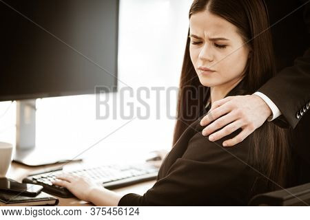 Sexual harassment at work. Male businessman puts hand on annoyed female assistant shoulder at workplace showing inappropriat behaviour. Two people man and woman conflict relations in modern office.
