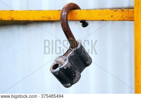 Old Rusty Lock. An Open Rusty Lock Hangs On A Yellow Iron Beam In The Open Air. The Balance Of Trust