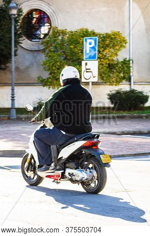 Back View Of Man Riding A Moto Scooter In Downtown Of Lugoj, Romania, 2020.