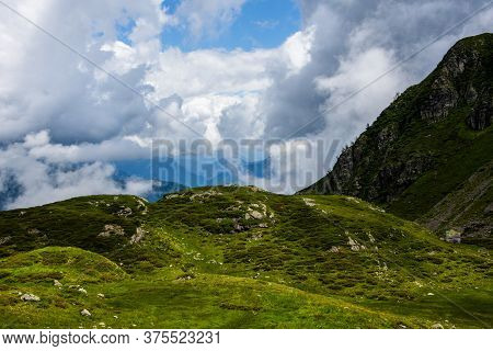 White Clouds, Blue Sky, Green Pastures And Spikes Of Granite Rock In The Lagorai In The Trentino Alp