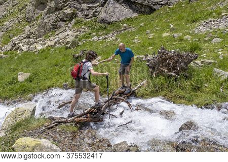 Man Helping A Woman To Cross A Mountain River In The Pyrenees Top View