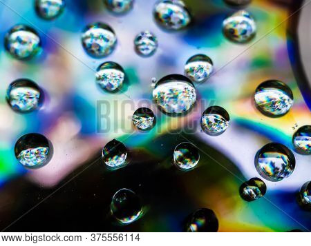 Drops Of Rain Water Are Falling On Cd Dix And Reflecting Sunlight. Yellow Blue And Red Light Is Bein