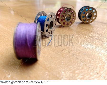 Four Bobbins Are Placed On Floor With The Far Away Bobbins At Focus.the Holes In The Bobbins Are Cle