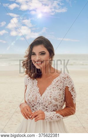 Beautiful Bride In Her Wedding Dress Posing For Photos On The Beach.