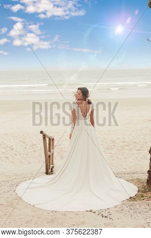 Beautiful Bride In Her Wedding Dress Posing For Photos On The Beach.