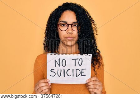 Young african american curly woman holding banner with no to suicide message with a confident expression on smart face thinking serious